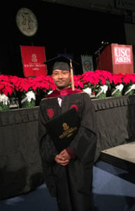 Student Ying Meng in cap and gown holding degree